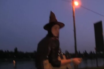 Девушка в костюме ведьмы развлекается с незнакомцем на улице после хеллоуинской вечеринки